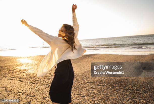 carefree woman dancing at beach against sky during sunny day - dancing for ned stock pictures, royalty-free photos & images
