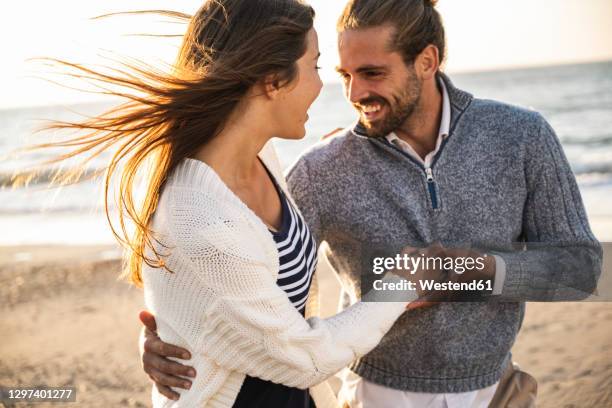 smiling young couple at beach during sunny day - long straight hair stock pictures, royalty-free photos & images