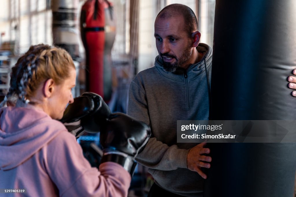 Female boxer practicing punches with coach