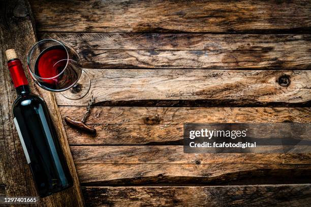 red wineglass and bottle shot from above on rustic wooden table. copy space - uva merlot imagens e fotografias de stock