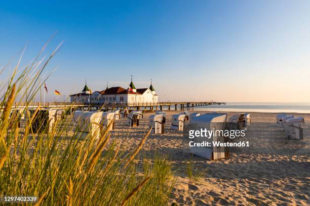 germany,mecklenburg-westernpomerania, ahlbeck, hooded beach chairs on sandy coastal beach with bathhouse in background - usedom photos et images de collection