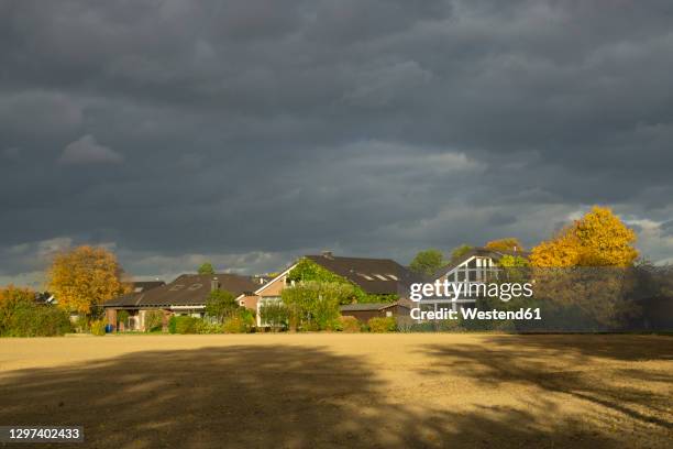 gray cloudy sky over suburb houses in autumn - suburbs stock-fotos und bilder