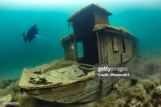 scuba diver swimming toward shipwreck sunken in lake atter - attersee stock pictures, royalty-free photos & images