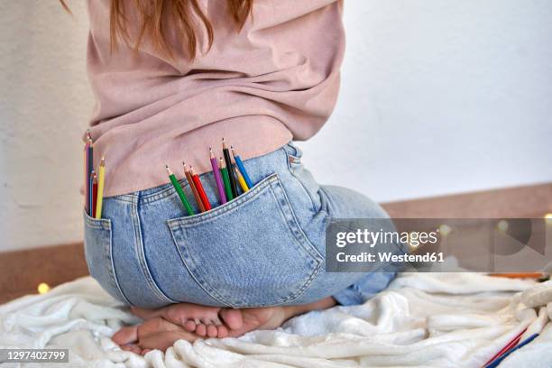 female artist with bunch of colored pencil in back pocket of jeans at home - back pocket photos et images de collection