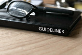 Selective focus of glasses, pen and black book title of Guidelines on wooden background.