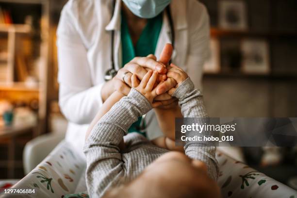 doctor holding feet and hands of a little baby boy - kids feet in home stock pictures, royalty-free photos & images