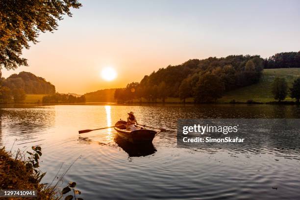 kvinna rodd en kanotbåt på sjön under solnedgången - rowboat bildbanksfoton och bilder