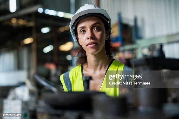young female engineer is working at small cnc machine production line while examining machine operate automation at factory. equipment and machine safety process. - werk in uitvoering stockfoto's en -beelden