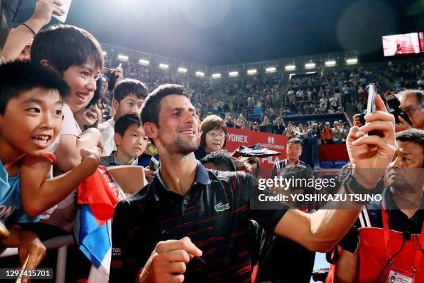 Le joueur de tennis serbe Novak Djokovic, numéro 1 mondial au classement ATP, fait un selfie avec de jeunes fans japonais après sa victoire au match...