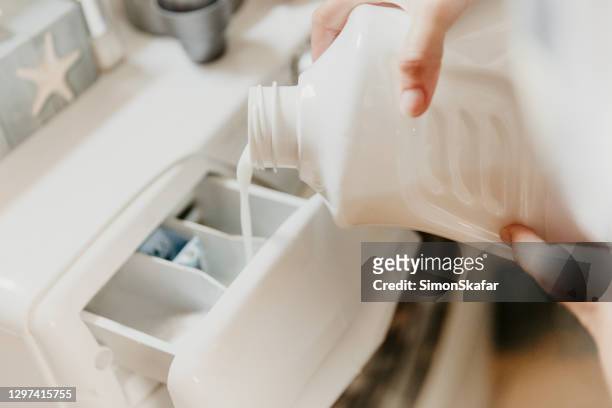 verter líquido de lavado en la lavadora - detergente líquido fotografías e imágenes de stock