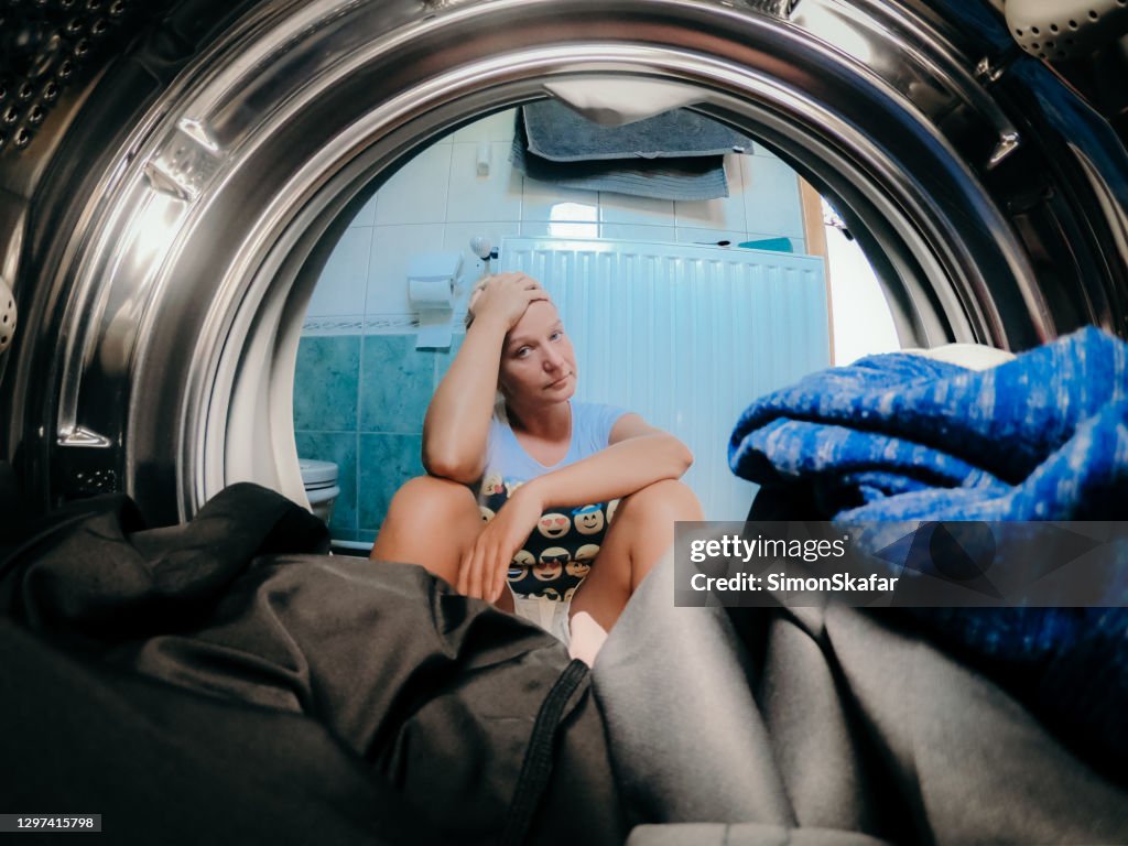Verstoorde vrouw die kleren in wasmachine bij badkamers bekijkt