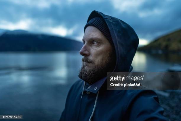 bebaarde visser portret: met regenjas door een fjord 's nachts - fisherman stockfoto's en -beelden