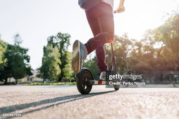 schüler fahren e-scooter durch die stadt - tretroller stock-fotos und bilder