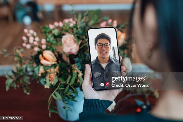 young woman receiving flower bouquet while having a video call with her love - zoom date stock pictures, royalty-free photos & images