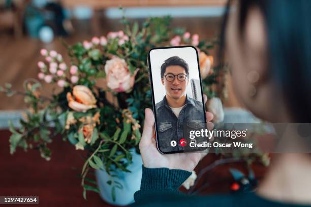 young woman receiving flower bouquet while having a video call with her love - långdistansförhållande bildbanksfoton och bilder