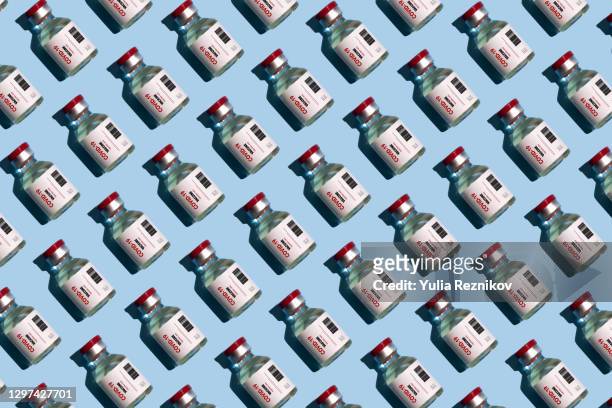 repeated vials with covid-19 vaccine on the blue background - covid 19 vaccine stock pictures, royalty-free photos & images