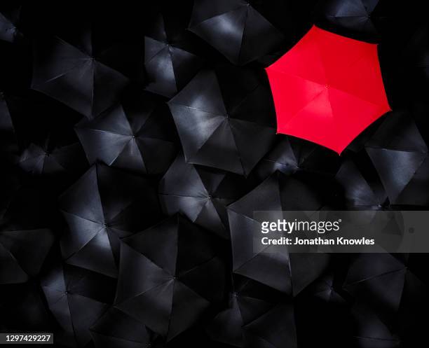 unique red umbrella - red and black background stock pictures, royalty-free photos & images