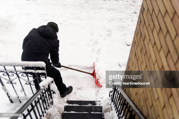 senior man shoveling snow from stair case on city street. - snow removal stock pictures, royalty-free photos & images