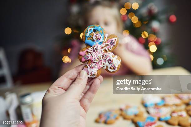 woman holding a gingerbread christmas decoration - gingerbread men 個照片及圖片檔