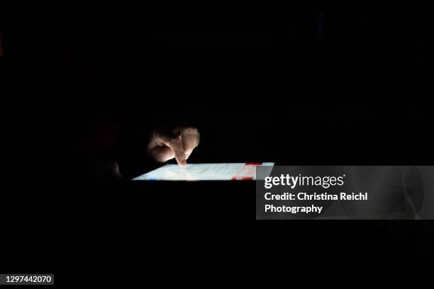 woman browsing on tablet in the dark - woman holding smart phone stock pictures, royalty-free photos & images