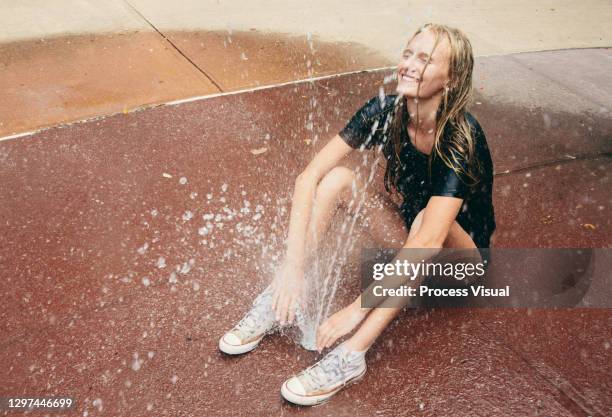 young woman playing in sprinkler - candid beautiful young woman face stock pictures, royalty-free photos & images