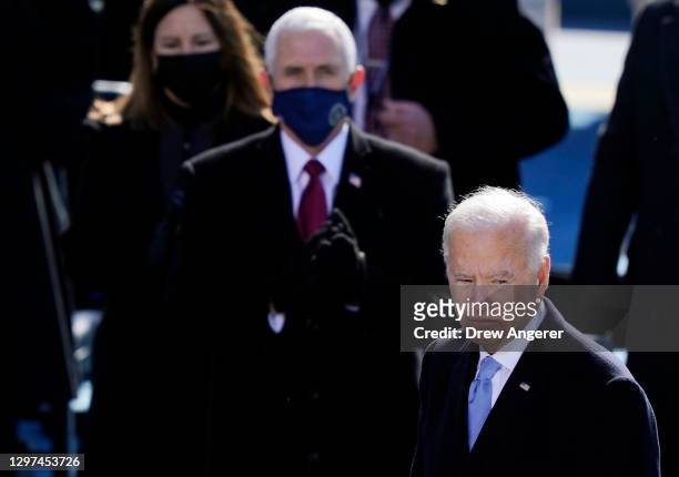 President Joe Biden pauses after delivering his inaugural address while former Vice President Mike Pence looks on the West Front of the U.S. Capitol...