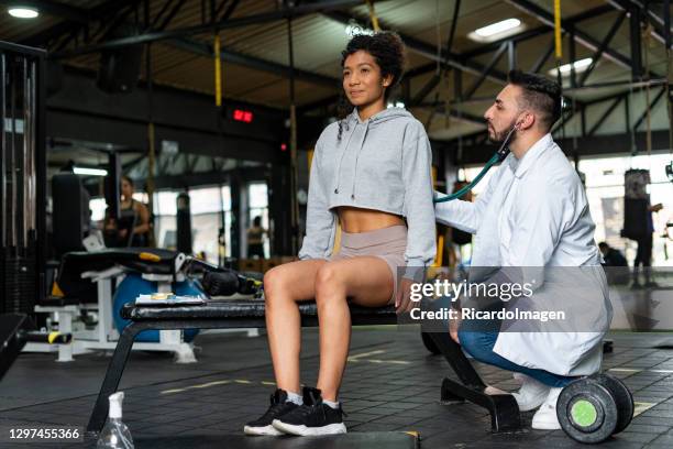 médico verifica uma jovem enquanto faz esportes na academia - sportman - fotografias e filmes do acervo