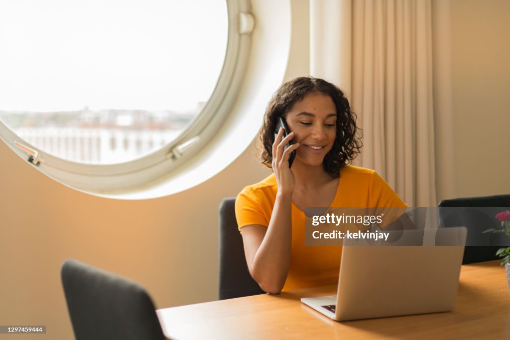 家庭辦公室快樂的年輕女子， 打電話和使用筆記型電腦