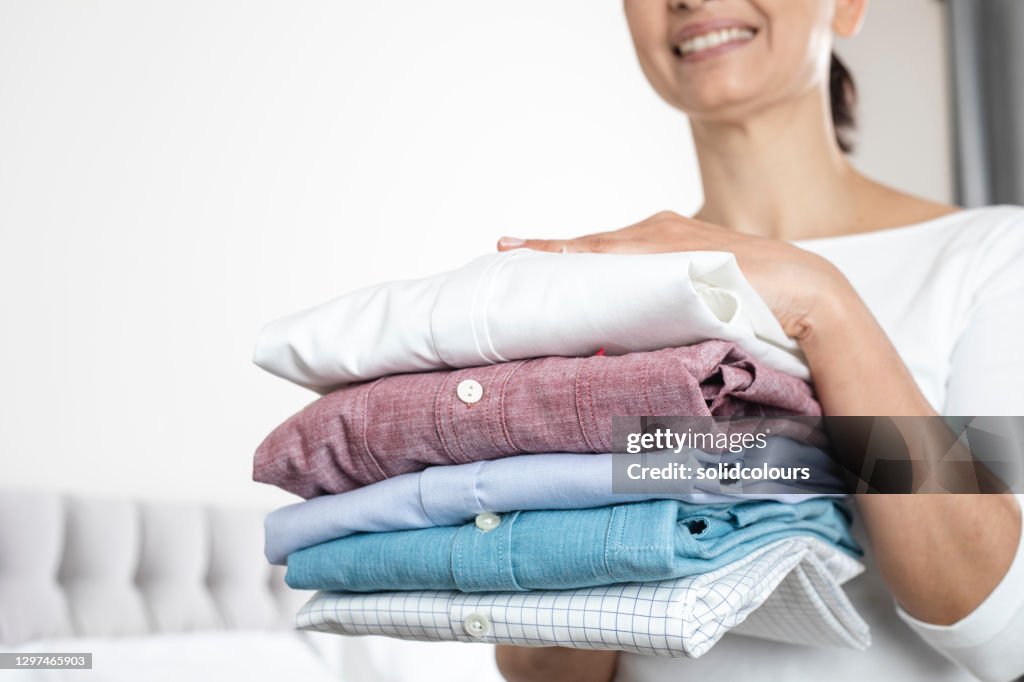 Woman Is Holding a Stack of Ironed and Folded Shirts