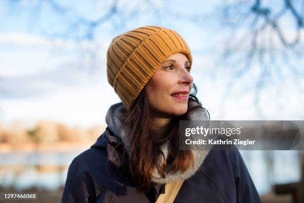 portrait of woman standing by a lake on a sunny winter day - autumn still life stock pictures, royalty-free photos & images