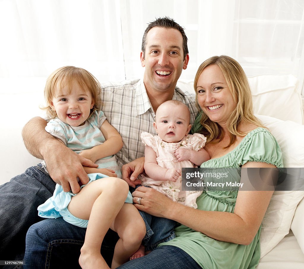 Portrait of smiling family with 2 young daughters.