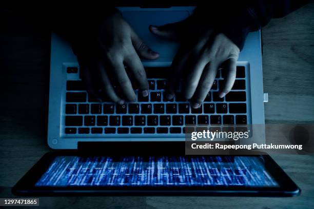 a computer programmer or hacker prints a code on a laptop keyboard to break into a secret organization system. internet crime concept. - web programmer stock pictures, royalty-free photos & images