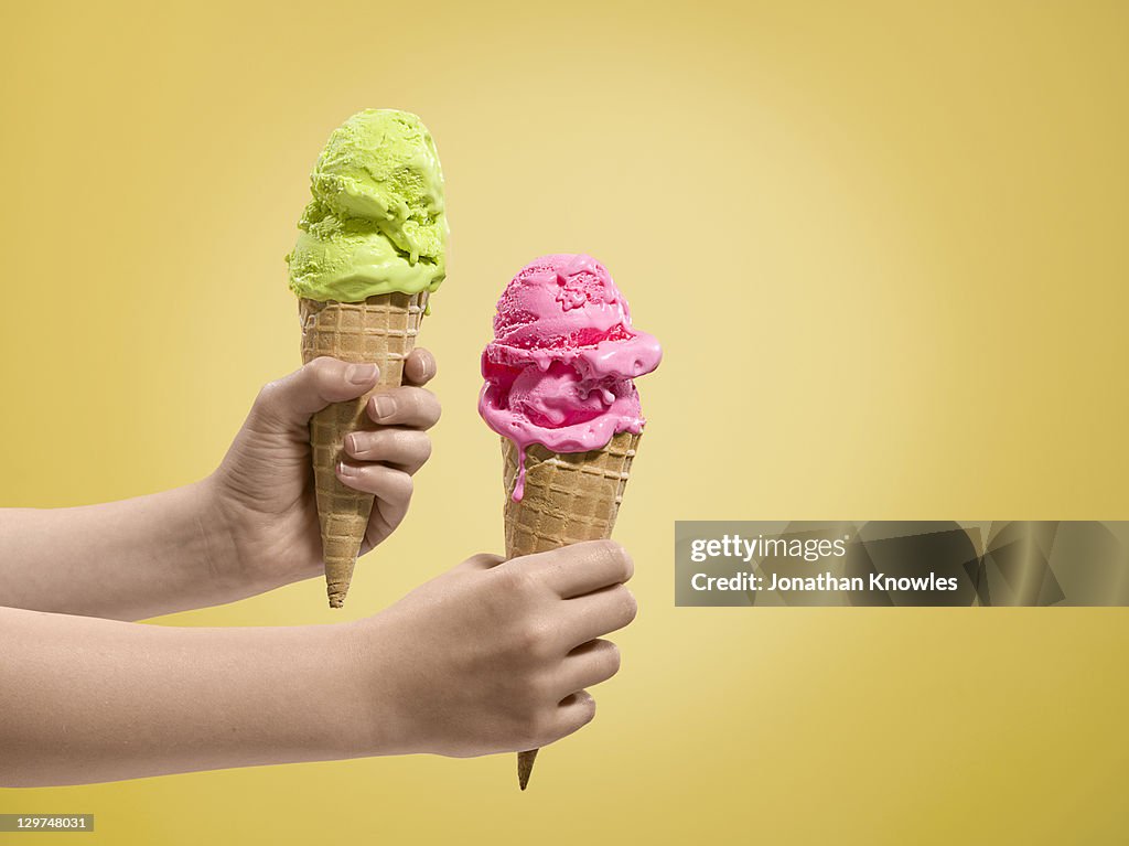 Hands holding ice-creams of different flavours.