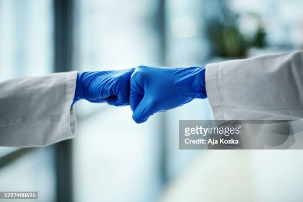 doctors fist greeting during pandemic. - surgical glove stock pictures, royalty-free photos & images