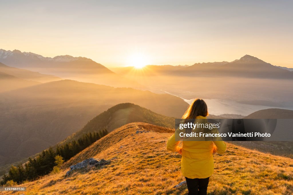 Woman gazing at Lake Como and mountains from high up, Italy.