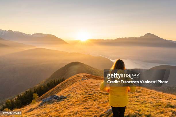 woman gazing at lake como and mountains from high up, italy. - sunrise contemplation - fotografias e filmes do acervo