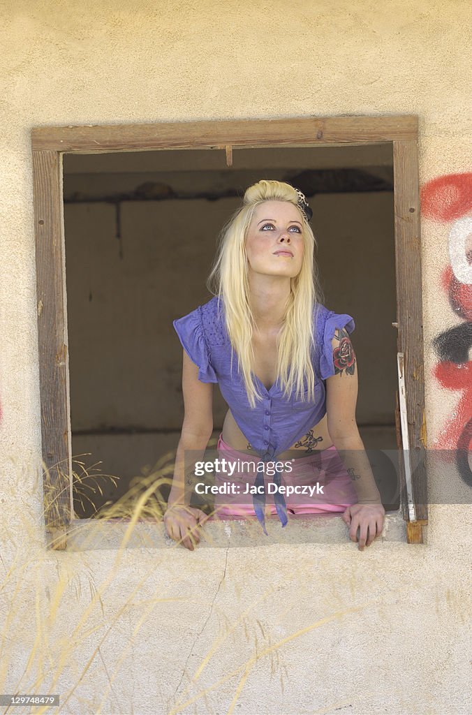 Young woman looking out of a broken window