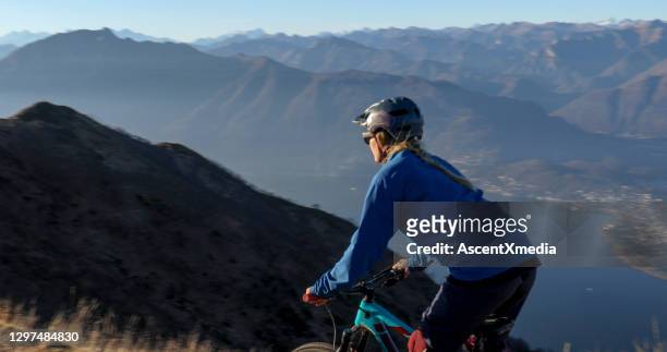 de vrouwelijke mountainbiker berijdt langs bergkam bij zonsopgang - lago maggiore stockfoto's en -beelden
