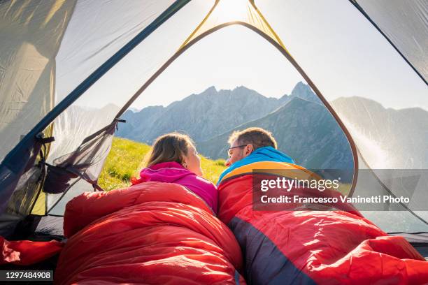 couple lying down in a tent on the mountains, italy. - saco de dormir fotografías e imágenes de stock