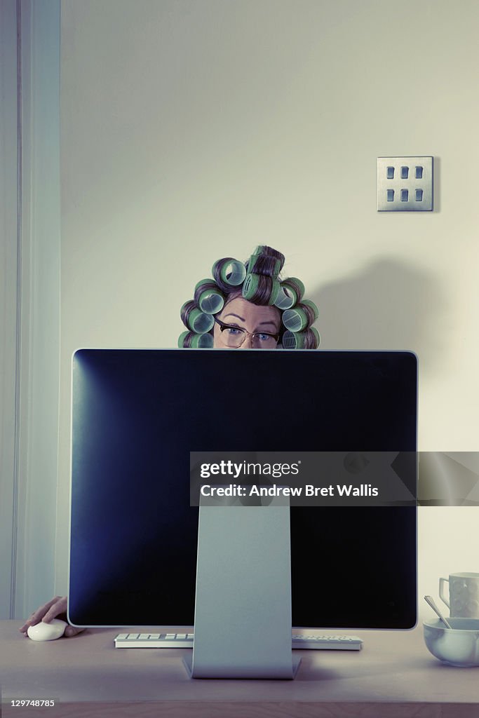 Woman with hair in rollers using computer at home