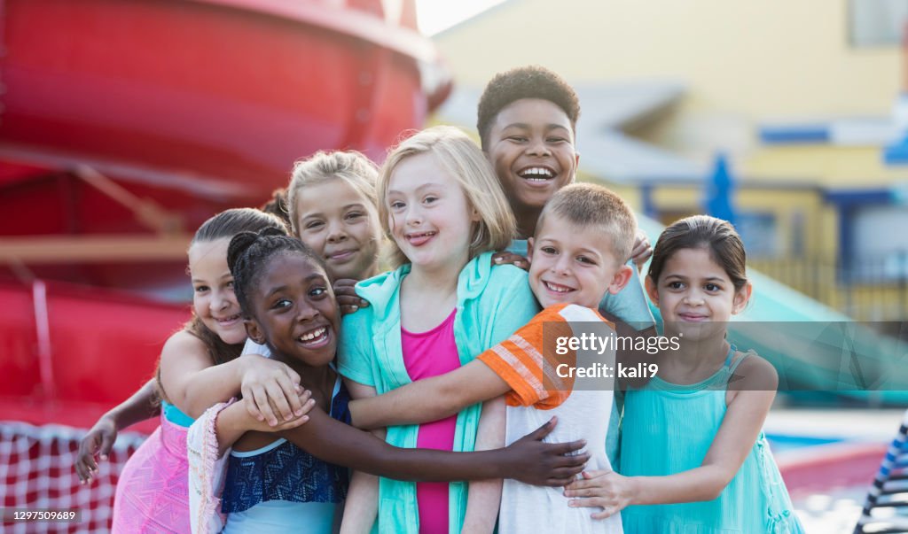 Girl with down syndrome, friends at water park hugging