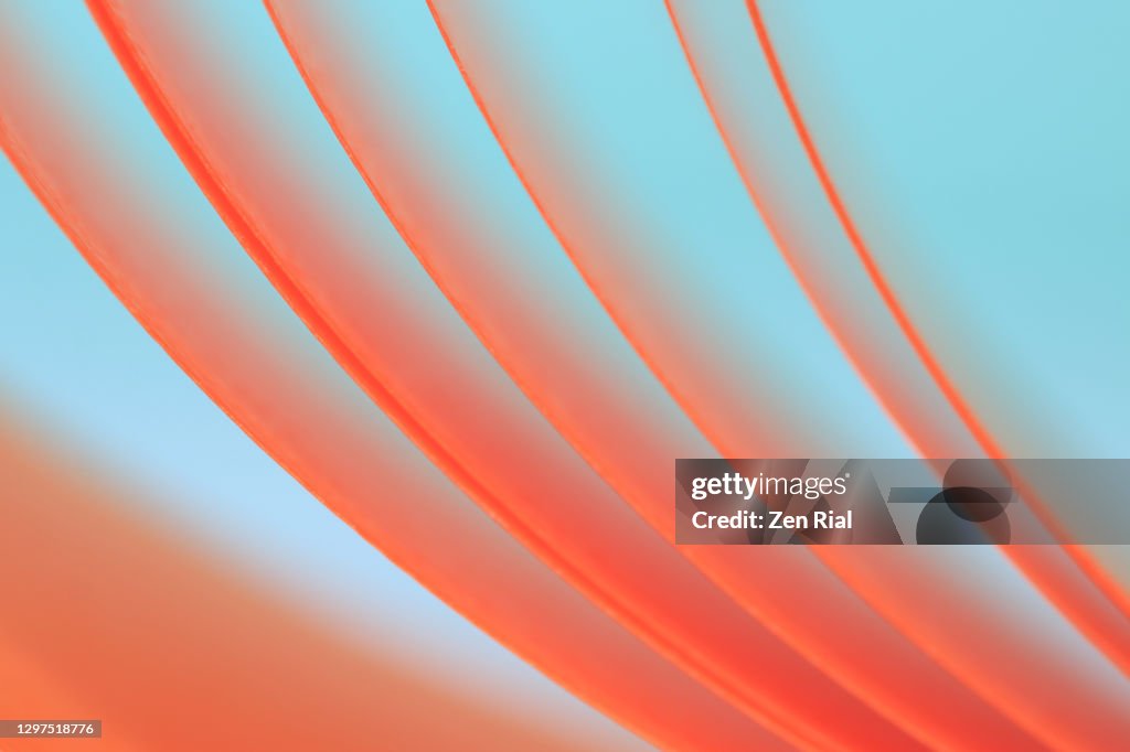 Peach colored ribbon unraveling from spool against bluish green background