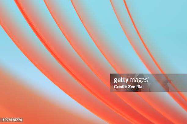 peach colored ribbon unraveling from spool against bluish green background - lightweight stock pictures, royalty-free photos & images