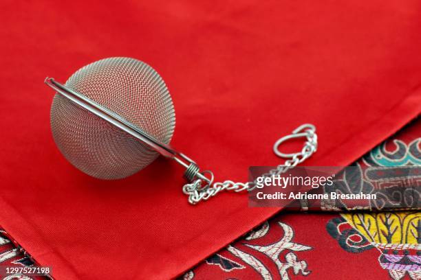 tea infuser on red embroidered chinese cloth - teesieb stock-fotos und bilder
