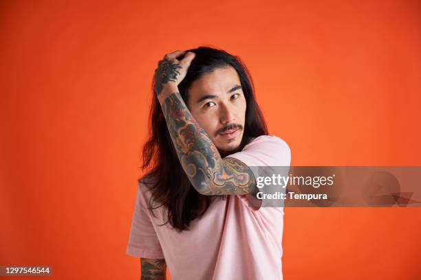 young man fixing his hair before having his portrait made. - asian man long hair stock pictures, royalty-free photos & images