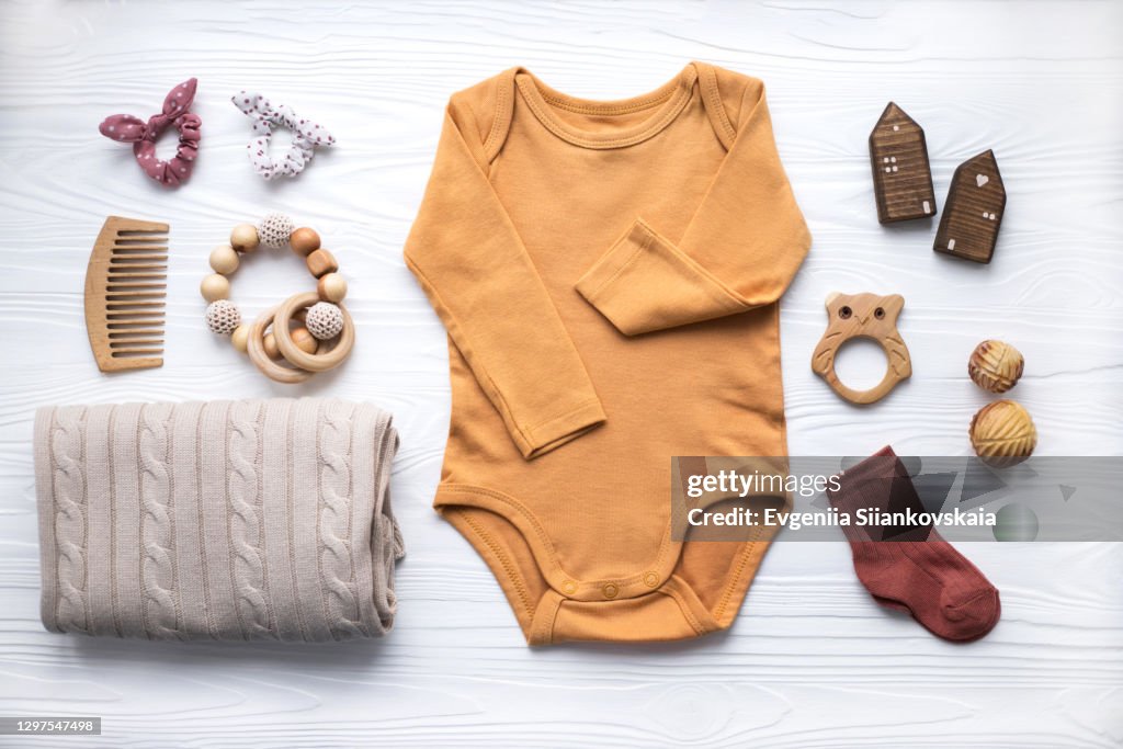Newborn baby clothing, blanket, wooden toys, teether and accessories on white background.