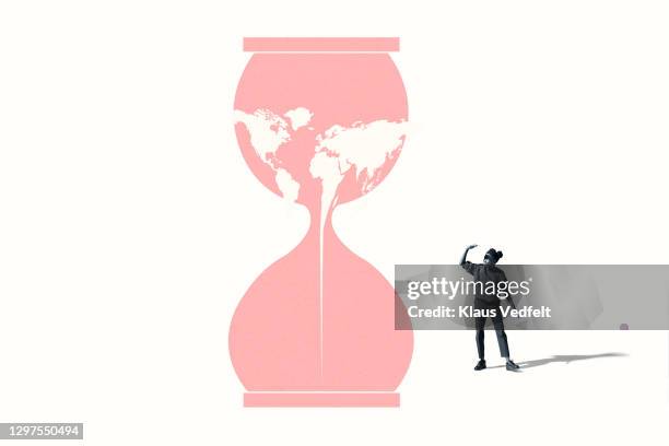 woman shielding eyes by hourglass with world map - big world stock pictures, royalty-free photos & images