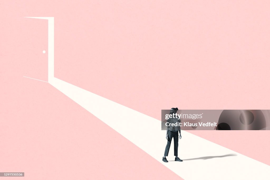 Young woman looking away against pink door