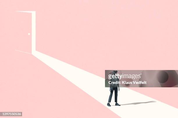 young woman looking away against pink door - expectativa imagens e fotografias de stock