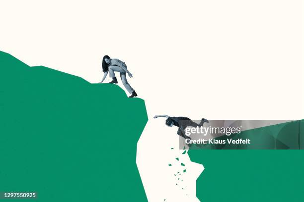 woman looking back at friend falling from cliff - breakup stock-fotos und bilder